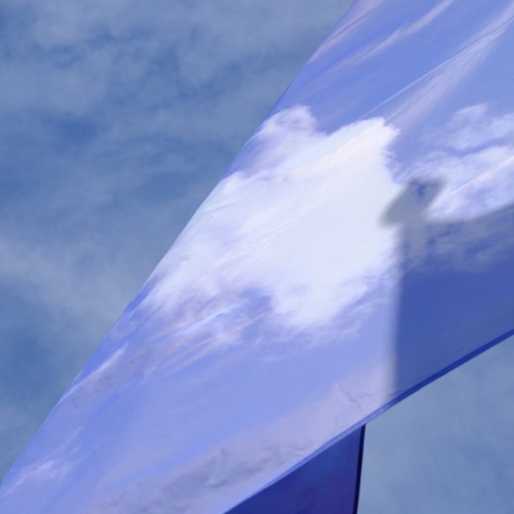 A close-up of a cloud-patterned flag, with a sky with clouds in the background.