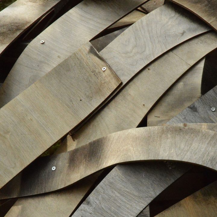 Brownish-gray, strip-like pieces of plywood from a work of art.