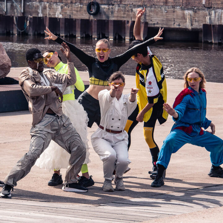 Tanssijajoukko kuvattuna eri asentoihin jähmettyneinä aurinkoisena päivänä.